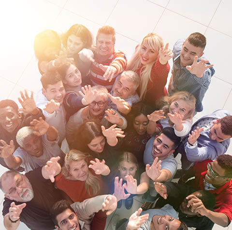 Multiethnic group of people standing together with hands up and smile