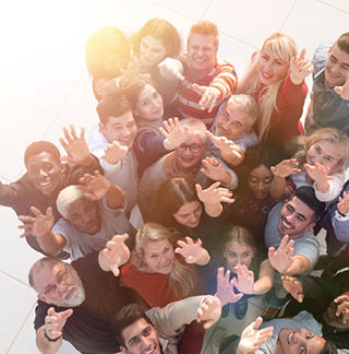 Multiethnic group of people standing together with hands up and smile