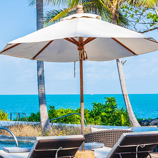 Umbrella and chair around outdoor swimming pool in hotel resort with sea ocean view for travel vacation