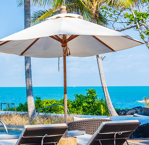 Umbrella and chair around outdoor swimming pool in hotel resort with sea ocean view for travel vacation